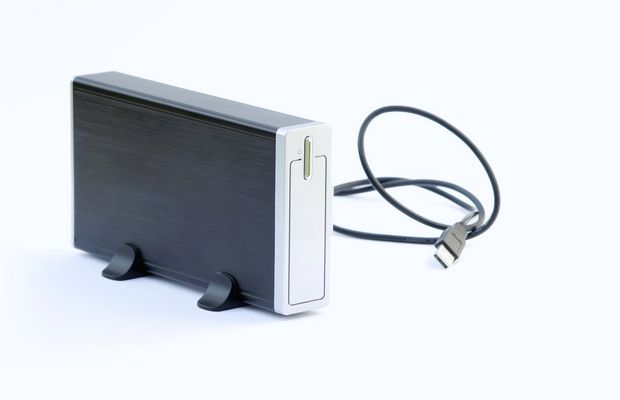 An external hard drive standing beside its USB cable