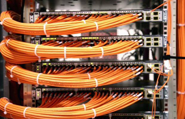 Orange network cables plugged into a rack of servers